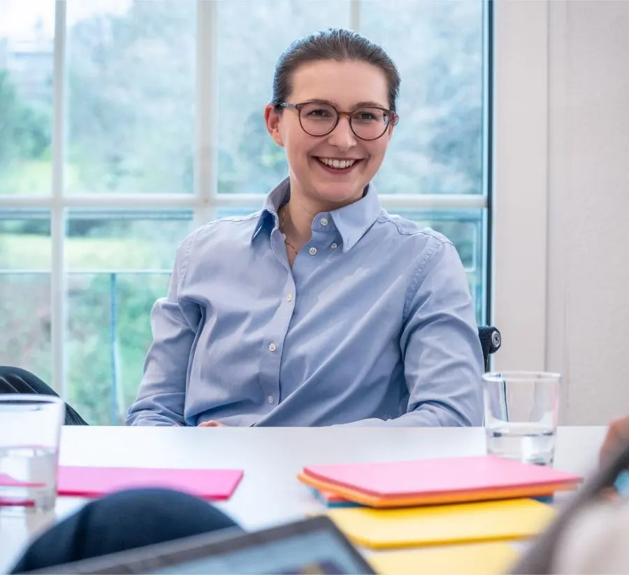 Bild einer lächelnden Frau mit Brille während eines Workshops.